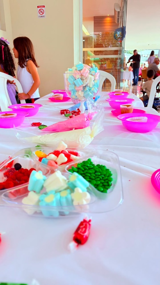 Mesa de oficina de cupcake com confeitos, doces coloridos e forminhas rosa