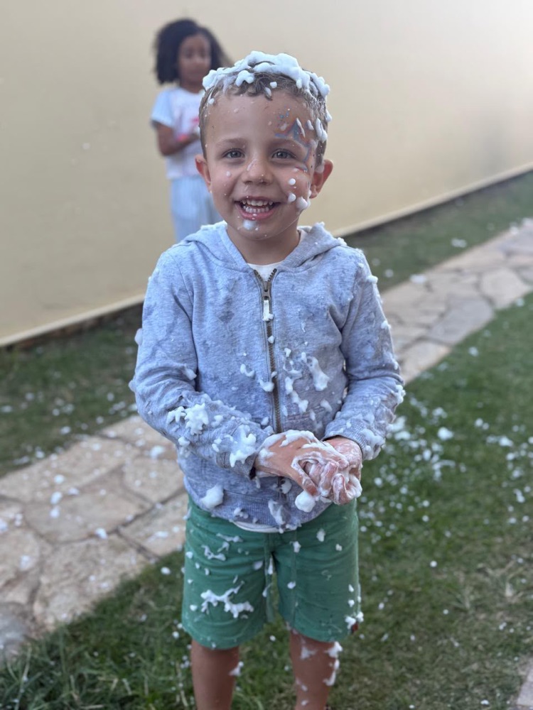 Menino rindo coberto de espuma na festa