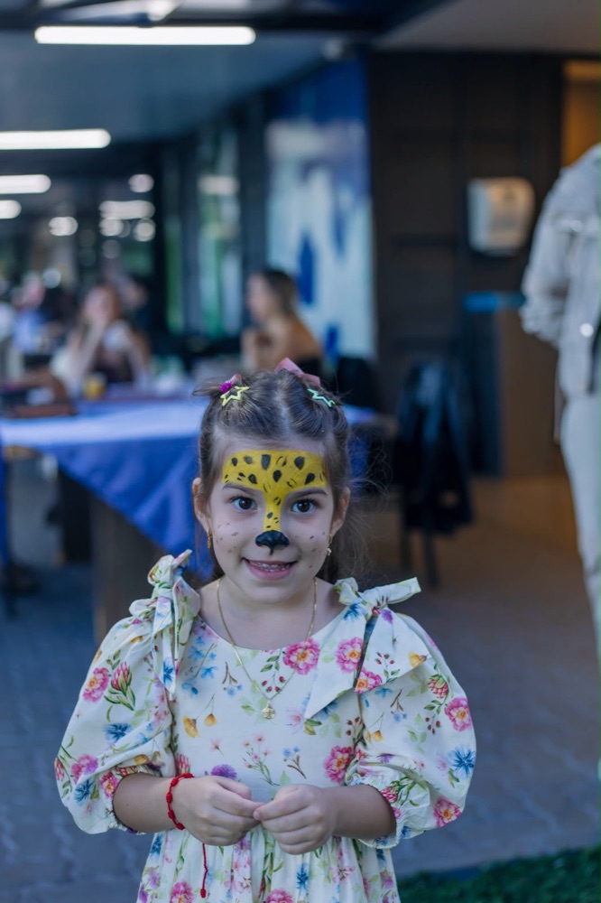 Menina com o rosto pintado de onça sorrindo para a câmera